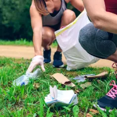 Aktywne plogging: dwie kobiety w rękawiczkach zbierają śmieci do worka podczas biegu.