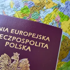 Polski paszport na tle globusa. Czy za paszport można zapłacić kartą? Podróże czekają!