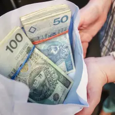 Paczki polskich banknotów 100 i 50 zł w kopercie. Przykład jak wyliczyć podatek od spadku.