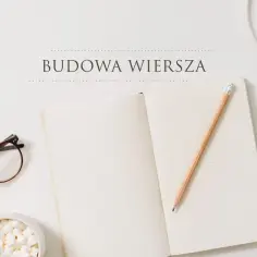 Okładka książki z napisem "Budowa wiersza", obok okulary, miseczka z piankami i ołówek na otwartym notatniku.