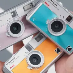 Trzy kolorowe aparaty Kodak Ektar H35N leżą w dłoni. Dowiedz się, jak wywołać zdjęcia z aparatu jednorazowego.