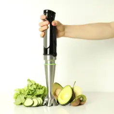 Ręka trzyma blender, obok sałata, cukinia, awokado i kiwi. Dowiedz się, jak wyczyścić końcówkę blendera ręcznego z resztek włóknistych warzyw.