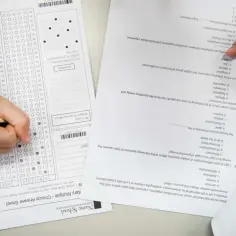 Ręka z ołówkiem zaznacza odpowiedzi na arkuszu. Ile trwa egzamin maturalny z biologii? To pytanie nurtuje wielu uczniów.