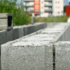 Szary bloczek do zalewania betonem czeka na budowie, by stać się częścią fundamentów.