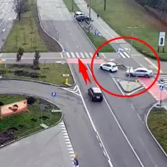 Skrzyżowanie z ruchem okrężnym, gdzie biały samochód wjeżdża na drogę podporządkowaną, ignorując znak. Czerwony okrąg zaznacza niebezpieczną sytuację.