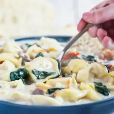 Gęsta, kremowa zupa z tortellini, szpinakiem i kawałkami mięsa, podana z chrupiącym pieczywem. Idealna na chłodne dni.