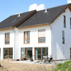 Nowa działka siedliskowa z nowoczesnymi domami w zabudowie szeregowej, z panelami słonecznymi na dachu i rowerami czekającymi na przejażdżkę.