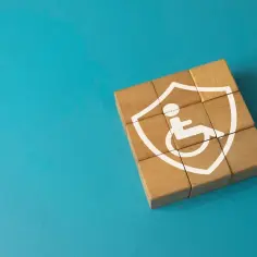 Drewniane klocki tworzące tarczę z symbolem osoby na wózku inwalidzkim.
