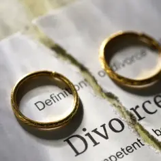 Dwa złote obrączki na przedartej kartce z napisem "Divorce".