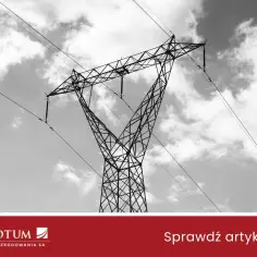 Wysoki słup energetyczny na działce, z którego zwisają kable, na tle chmur.