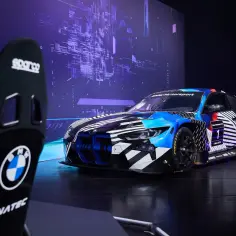 Wyścigowy BMW M4 GT3 z numerem 1, w dynamicznych barwach, gotowy do startu. Obok fotel kierowcy Sparco.