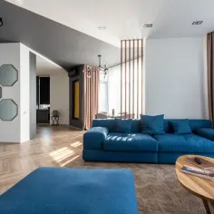 Nowoczesny salon z granatową kanapą, drewnianą podłogą i ozdobnymi lustrami.