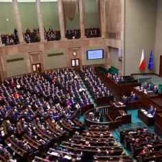 Widok na salę plenarną Sejmu RP z posłami siedzącymi w ławach.