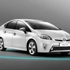 Biały Prius 3, hybrydowy samochód, prezentuje się elegancko na tle szarego tła, otoczony niebieską poświatą.