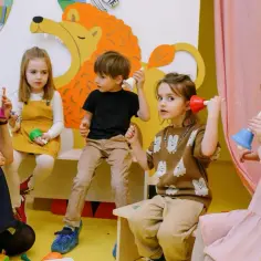 Dzieci na zajęciach muzycznych, podczas dnia motyla, dzwonią dzwoneczkami. Nauczycielka zachęca do zabawy.