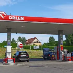 Stacja Orlen z dystrybutorami paliwa i samochodami. Zastanawiasz się, ile zarabia kasjer na Orlenie?