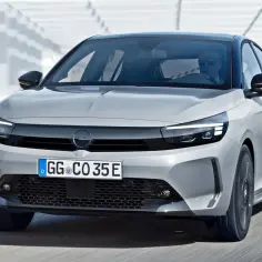 Nowy Opel Corsa 2023 w kolorze srebrnym, z nowoczesnymi światłami LED i czarnym dachem, pędzi po drodze.
