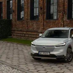 Nowa Honda HR-V w kolorze srebrnym zaparkowana na brukowanym podjeździe przed ceglanym budynkiem.
