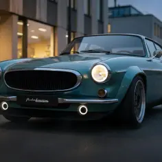 Klasyczny Volvo P1800 w turkusowym kolorze, z chromowanymi detalami i nowoczesnymi felgami, prezentuje się elegancko na tle miejskiej architektury.