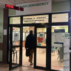 Mężczyzna wchodzi do placówki ZUS, gdzie sprawdzić umowy zlecenia. Widoczny napis "Informacja w sprawach emerytalno-rentowych".