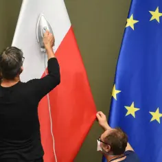 Dwaj mężczyźni przygotowują flagi Polski i UE. Jeden prasuje polską flagę, drugi poprawia unijną. Czy to zapowiedź polexitu?