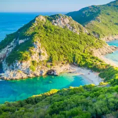 Idealna Grecja na wakacje: malownicza zatoka z piaszczystą plażą, turkusowa woda i zielone wzgórza.