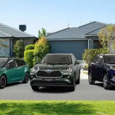 Trzy modele Toyota: zielony kombi, ciemnozielony Highlander i granatowy RAV4 Plug-in Hybrid, zaparkowane przed domami.