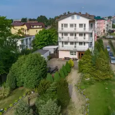 Pensjonat Kojak w Jastrzębiej Górze, otoczony zielenią, z parkingiem i miejscami do wypoczynku.