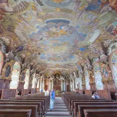 Wrocławskie muzea zachwycają. Wnętrze z barokowym freskiem na suficie, portretami i drewnianymi ławami.