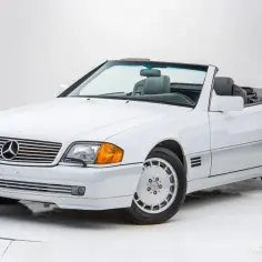 Biały kabriolet Mercedes-Benz SL500 z lat 90. z opuszczonym dachem, gotowy na letnią przejażdżkę.