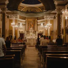 Wnętrze kościoła z wiernymi na ławkach. W tle ołtarz i obraz. Czy to miejsce, gdzie płaci się podatek na kościół?