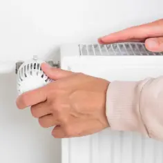 Dłoń regulująca termostat grzejnika.