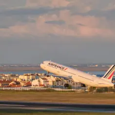 Samolot Air France startuje na tle miasta i morza.