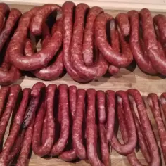 Dwie linie świeżych, wędzonych kiełbas na drewnianym blacie. Zastanawiasz się, ile czosnku do kiełbasy?
