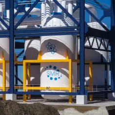 Nowoczesne reaktory SMR, czyli małe reaktory modułowe, w białych cylindrach z niebieskim logo atomu. To przyszłość energetyki jądrowej.