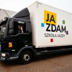 Ciężarówka szkoły jazdy "JA ZDAM" z napisem informującym o kursach na prawo jazdy kategorie B, B+ i kwalifikacji wstępnej. Kierowca pozdrawia.
