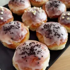 Szybkie pączki z piekarnika, polane lukrem i posypane czekoladą lub białymi perełkami. Idealne na szybką przekąskę.