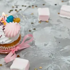 Uroczy cupcake z różową wstążką i ozdobami, idealny jako alternatywa dla tortu urodzinowego.