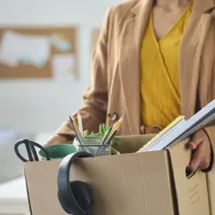 Kobieta z pudełkiem rzeczy osobistych, zastanawia się, czy można złożyć wypowiedzenie na zwolnieniu.