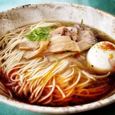 A miseczce shoyu ramen z makaronem, plastrami mięsa, bambusem i jajkiem na twardo, posypanym papryką.