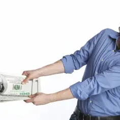 Mężczyzna z zakręconymi włosami i brodą szarpie stos banknotów dolarowych, jakby walczył o to, kto płaci czynsz za mieszkanie.