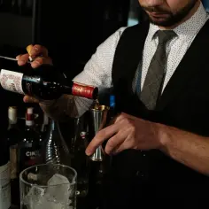 Barman nalewa wermut z butelki do metalowego jiggera.