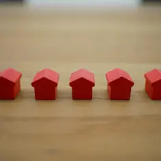 Pięć czerwonych, drewnianych domków na drewnianym tle. Wzór zaświadczenia o samodzielności lokalu.