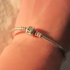 Srebrna bransoletka Pandora na nadgarstku, z jednym charms'em. Prosty sposób, jak założyć bransoletkę Pandora.