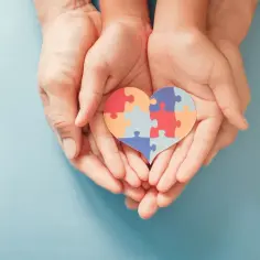 Dłonie trzymają serce z puzzli. To symbol wsparcia dla osób z autyzmem, a nie wykluczenia.
