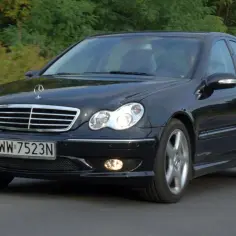 Czarny Mercedes-Benz W203 z tablicą rejestracyjną WW 7523N jedzie po drodze wśród zieleni.