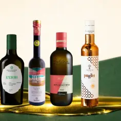 Pięć butelek oliwy z oliwek extra virgin na zielonym tle z płynną oliwą.