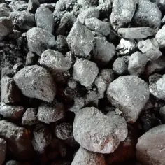 Górnicy wydobywają kamień węgielny, czarne bryły lśniące w świetle.