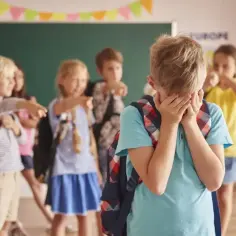 Chłopiec płacze, bo inne dzieci wskazują na niego palcami. Gdy dziecko nie chce chodzić do szkoły, szukać pomocy można u psychologa.