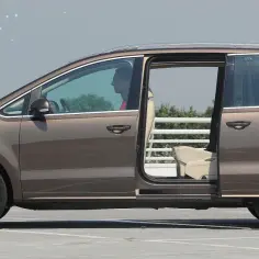 Brązowy minivan z otwartymi drzwiami, widoczny kierowca. Ten mpv za niski, by wygodnie wsiadać.